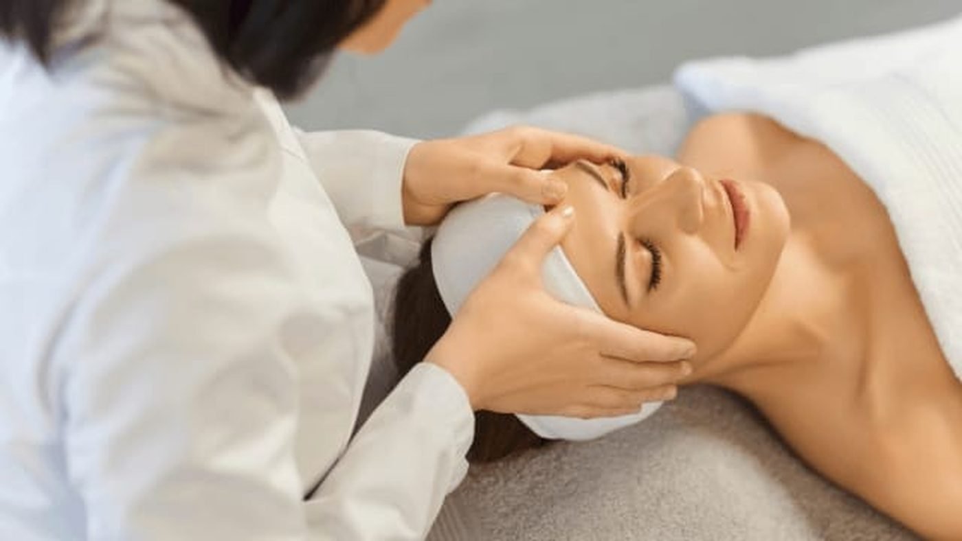 A practitioner examining a client's face before a treatment